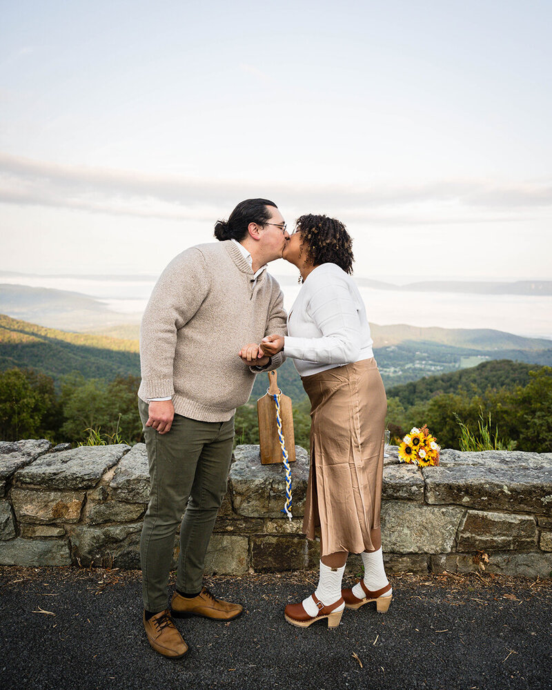 A couple eloping at Timber Hollow Overlook in Shenandoah National Park pinky promise and go in for their first kiss at the conclusion of their ceremony.