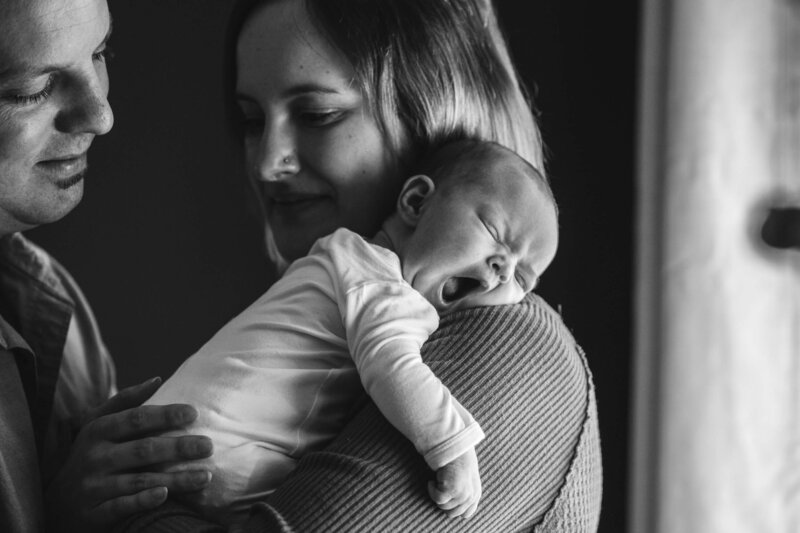 new parents admire their yawning newborn