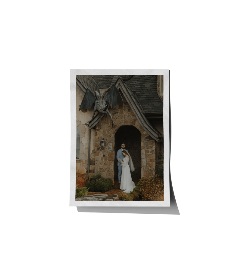 A bride and groom standing in a doorway with a gargoyle above them, representing a wedding coordination by Birdie June Events.