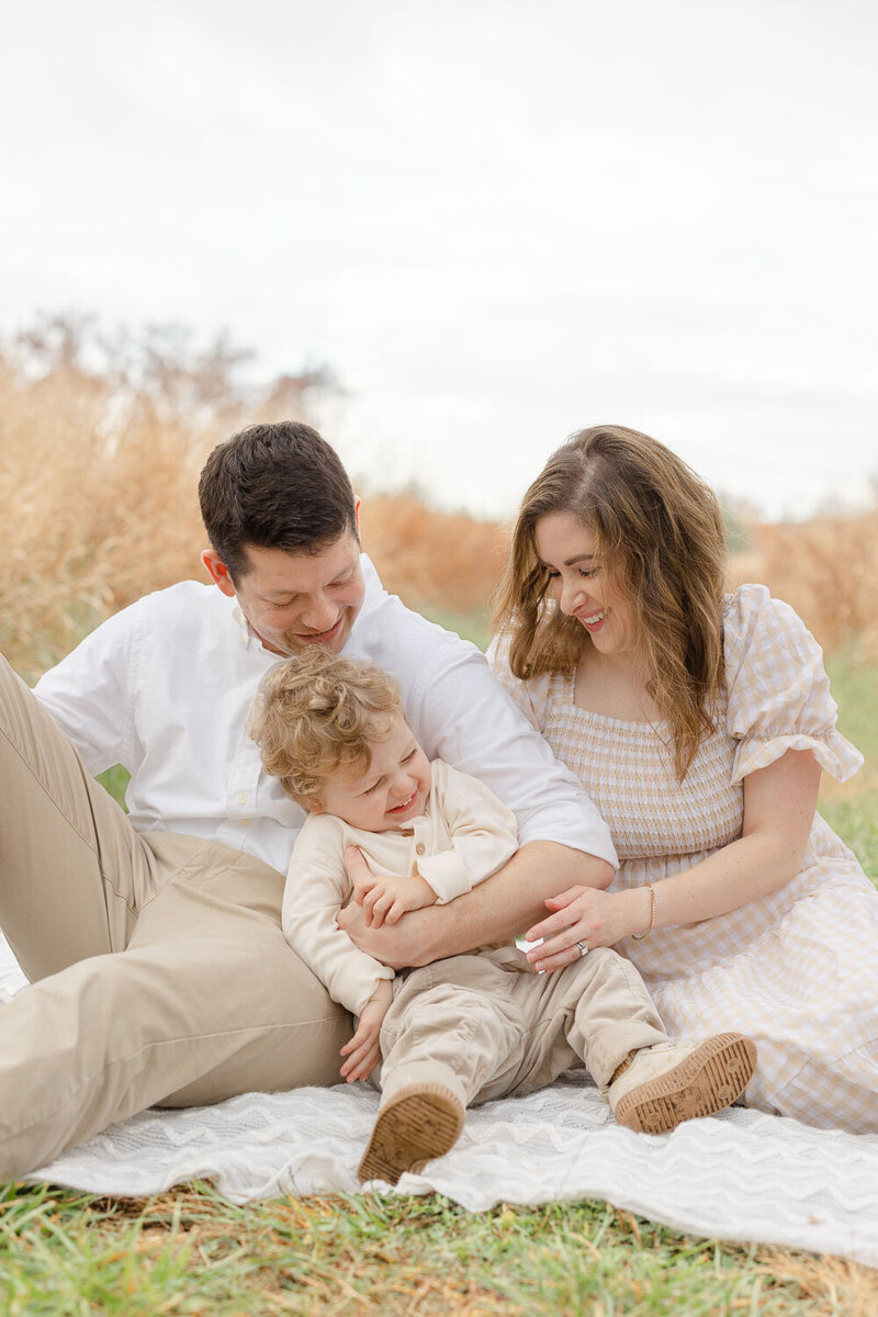 Family of 3 sitting and laughing during a session in Manassas, Virginia