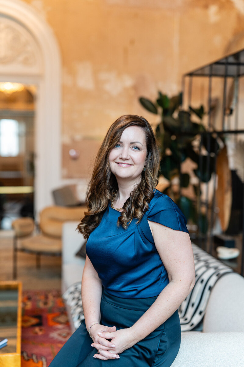 Bryony Williams in blue shirt sitting on a sofa
