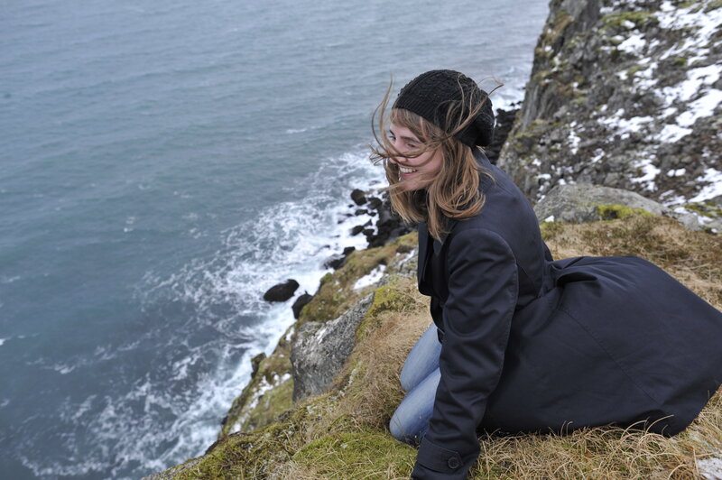 Top raleigh wedding photographer in black trench coat and hat overlooking a cliff in iceland