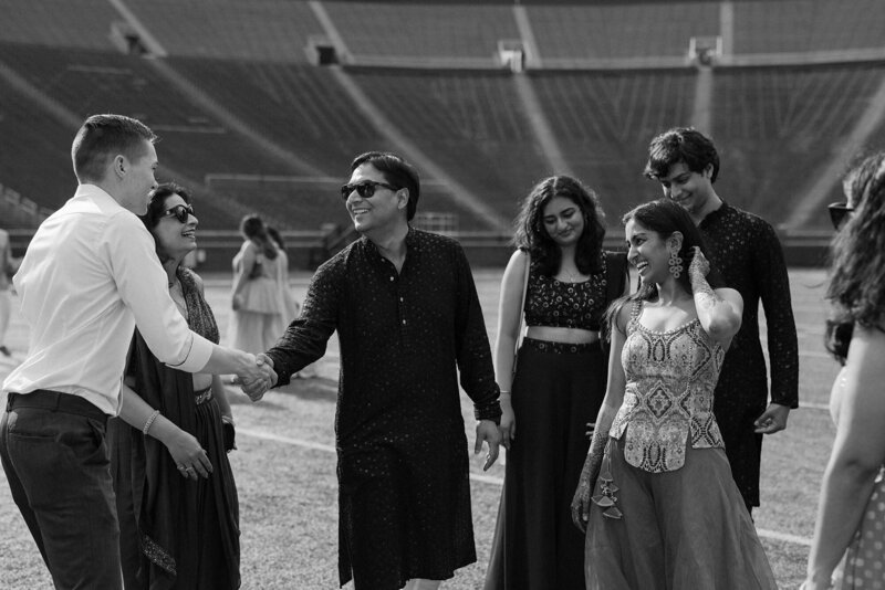 A group of people smiling as two people shake hands 
