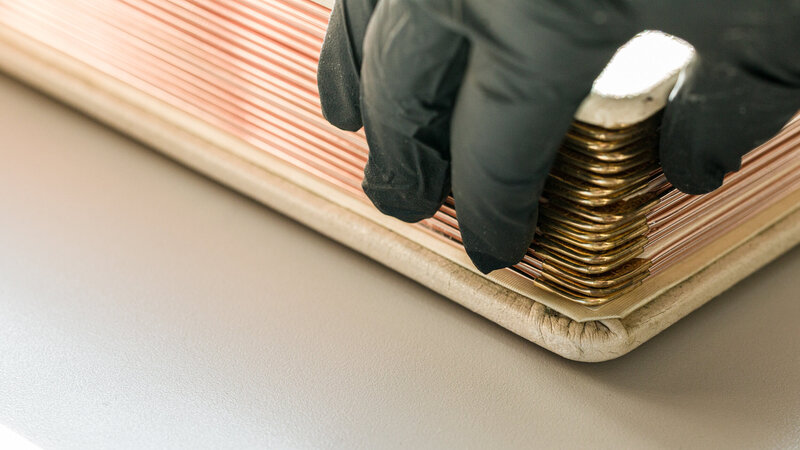 A black-gloved hand gently touching the side of an old wedding album, ensuring careful preservation.