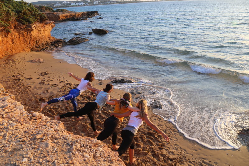 Four Yogis in Warrior 3 Pose on the Beach of the Mediterranean