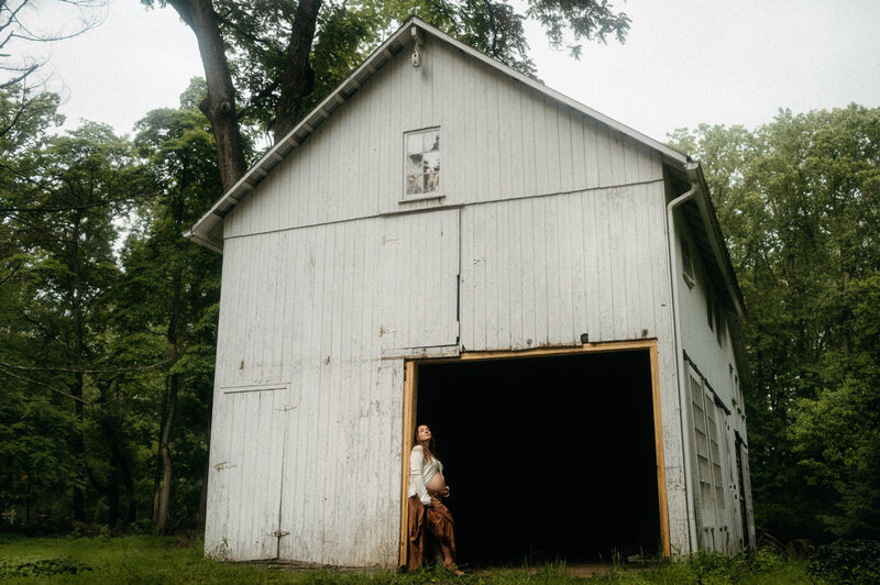 Woman sits in a water trough with cowgirl boots and a bottle of whiskey. 