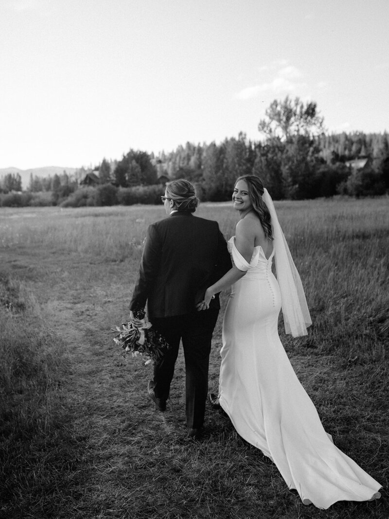 Two brides holding hands and one looks over her shoulder back at the camera, representing a wedding planned by Boise event planner Perfect Thirds & Co. 