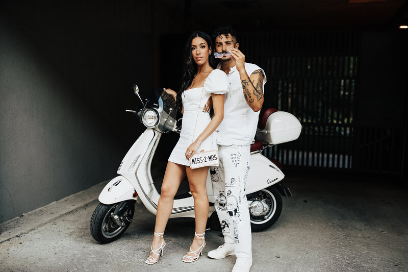 married couple posing in front of scooter