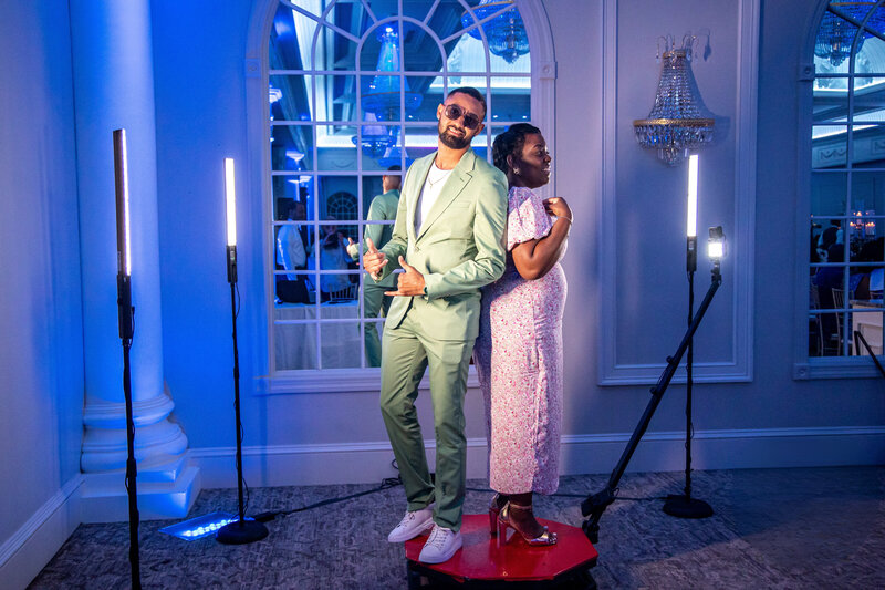 A man and a woman standing on a 360 booth posing for a picture