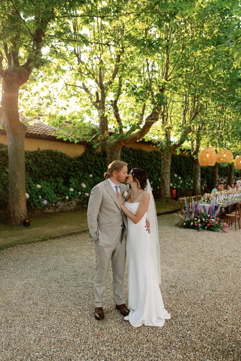 bride and groom kissing by wedding reception table