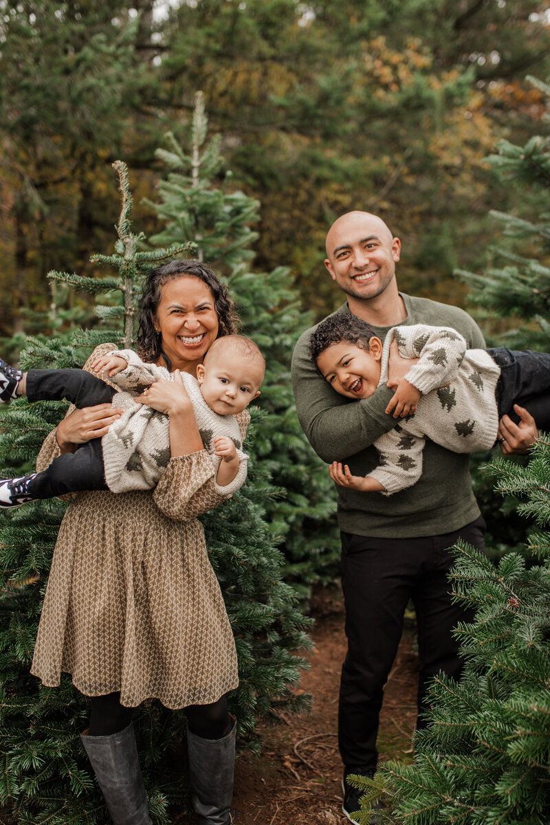 Family with two children smiling in a Christmas tree farm