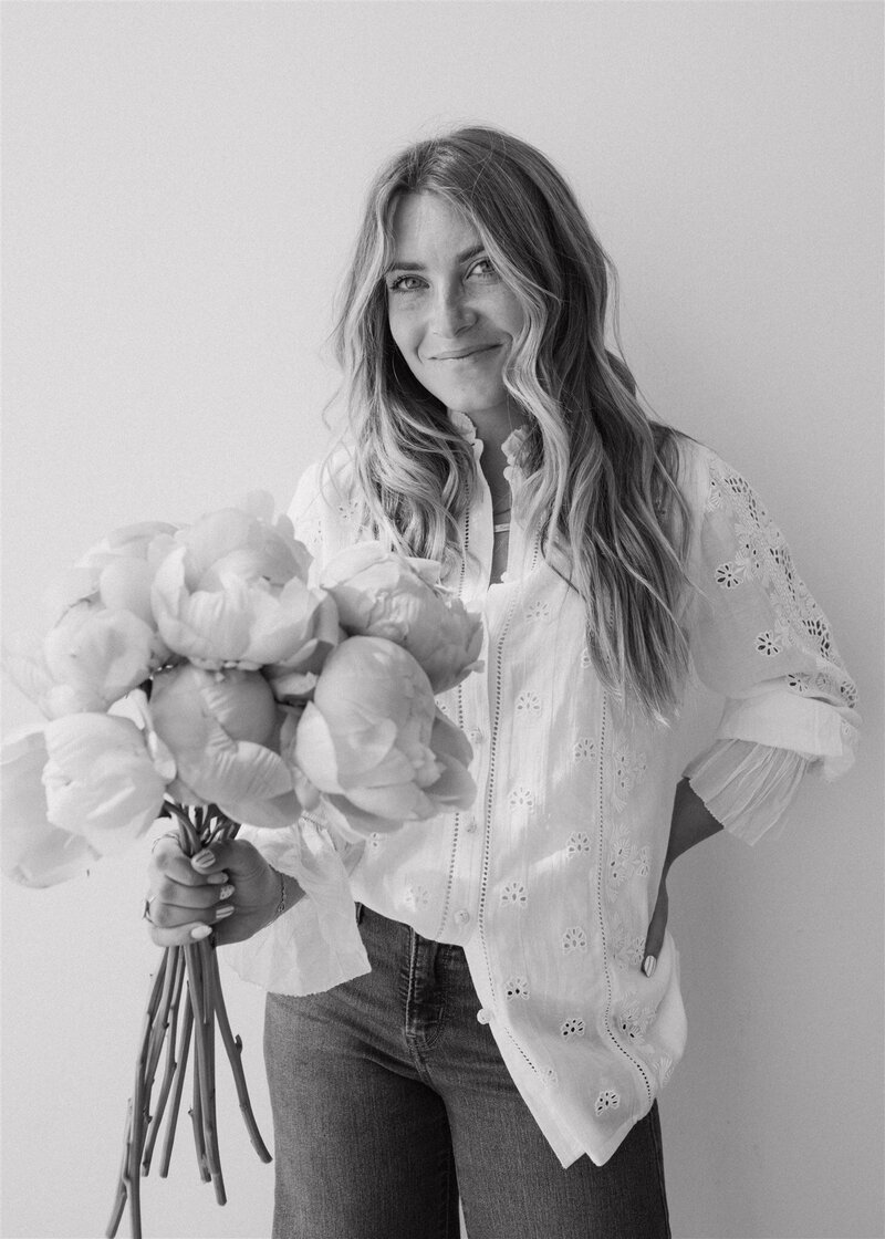 Black and white image of floral designer holding bouquet of peonies