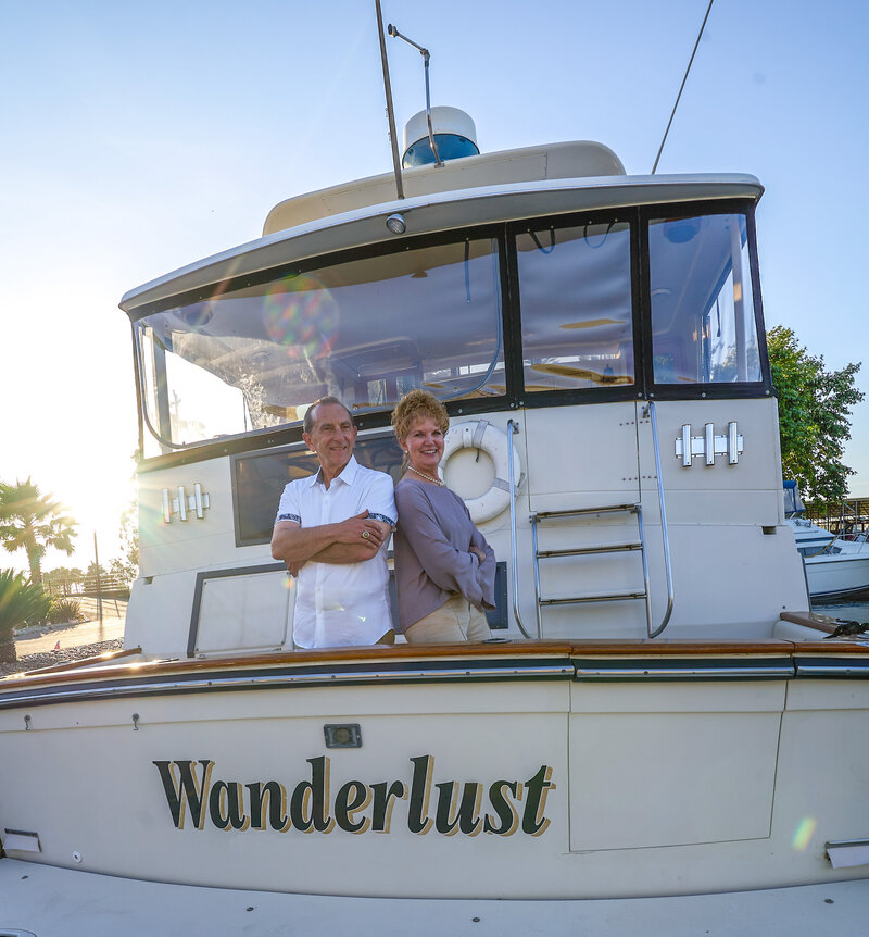 wealthy couple happy on a yacht smiling with the sunset in background