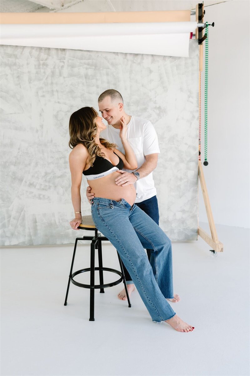 Couple touching noses and embracing baby bump