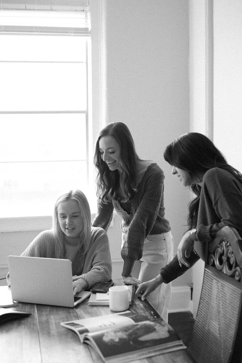 Black and white image of three women working on a laptop at a table