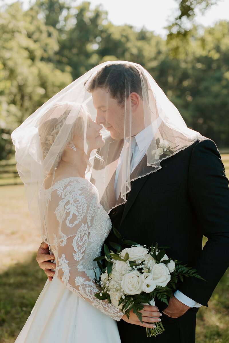 bride and groom holding hands walking in a green pasture with horses in Richmond, Virginia
