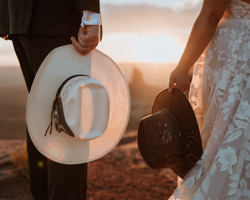 bride and groom holding cowboy hats