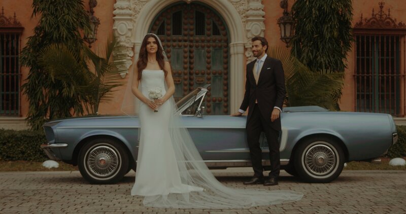 bride and groom standing next to vintage car