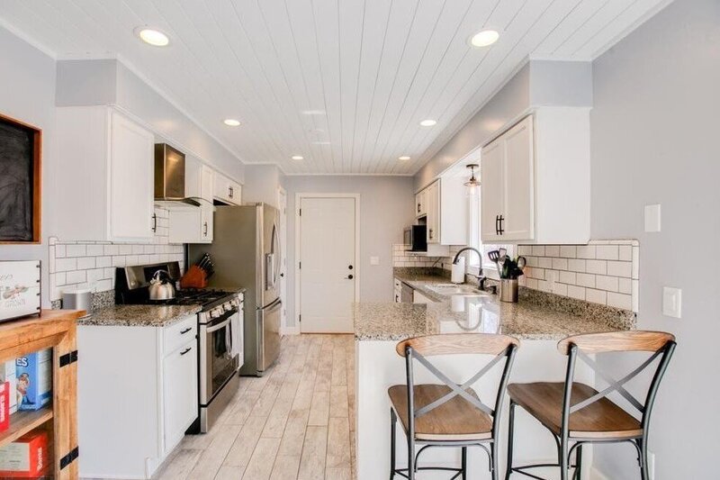 modern, bright kitchen with white cabinetry and wood paneling accents