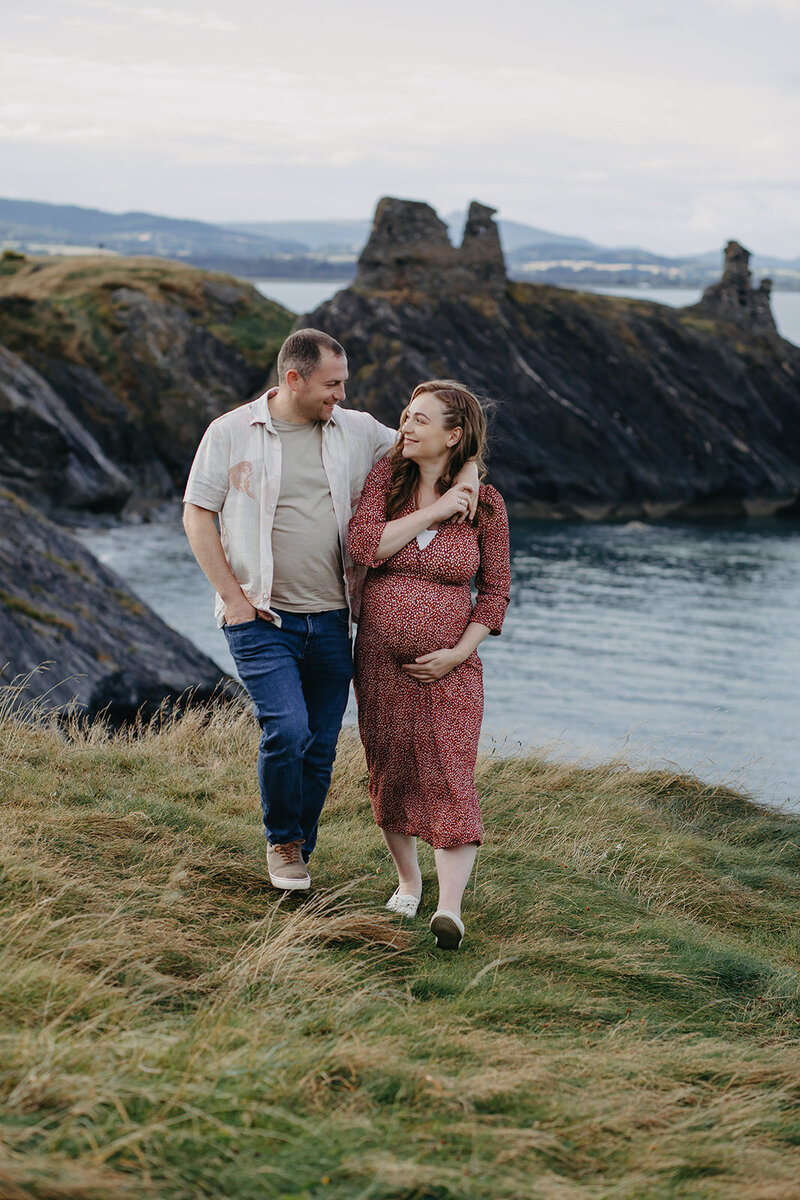 Maternity photoshoot on the dramatic cliffs of Ireland, Wicklow, with the expectant mother standing gracefully against the rugged coastal backdrop.