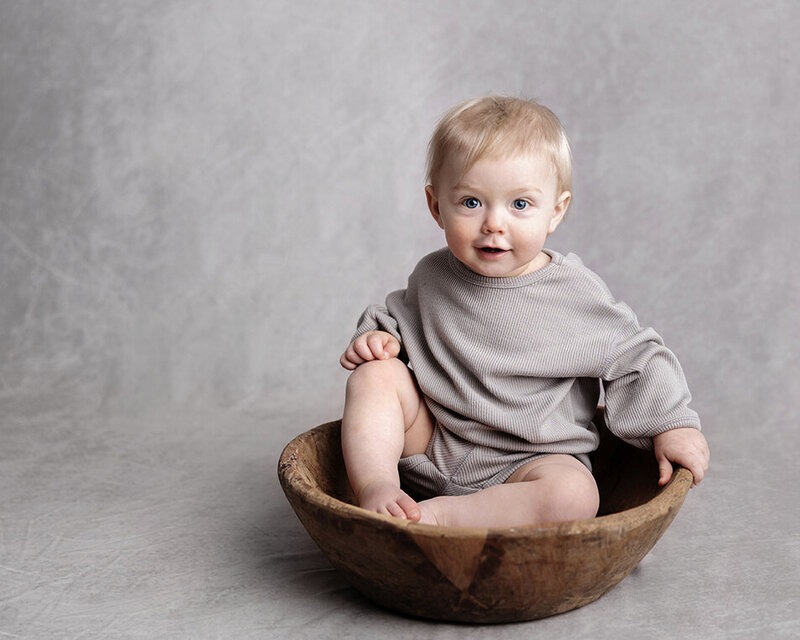 Boy sits in wooden bowl for his first birthday session in Murrysville portraits.