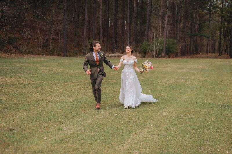Newlyweds run in their wedding outfits near the forest