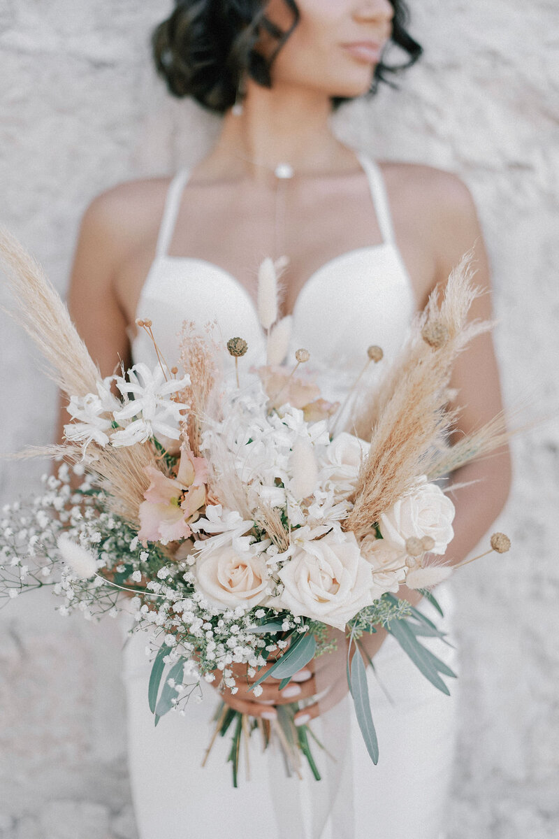 bouquet-flowers-is-hands-bride-leaning-against-wall-house-cropped