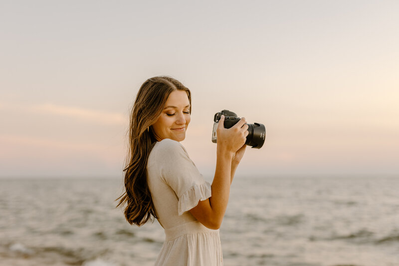 woman standing in tall grass holding a camera