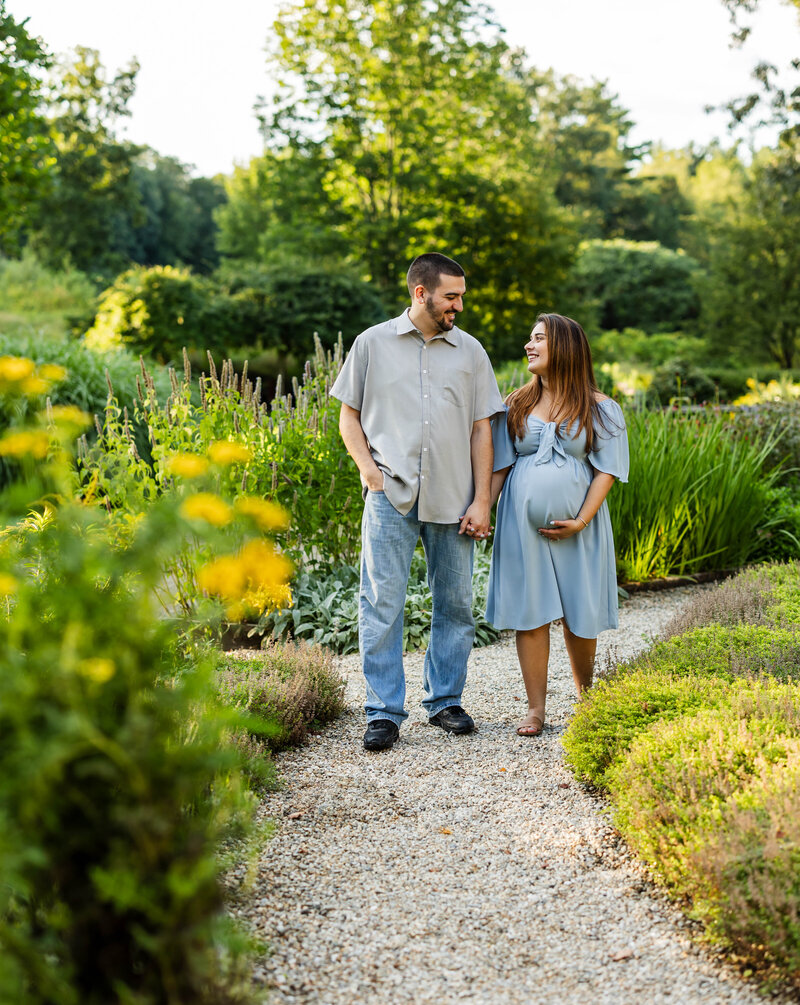 Maternity photos at Beaver Brook Association in Hollis, New Hampshire husband holds wife's hands and she holds her baby bump