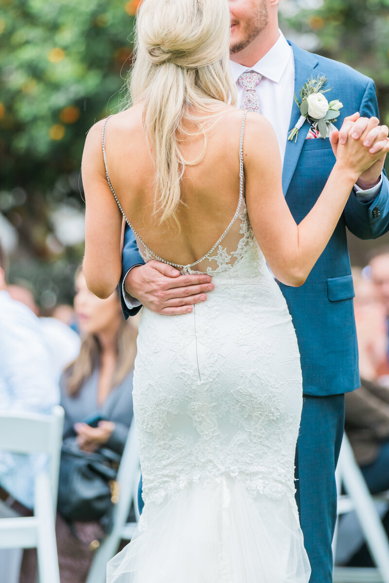 A couple dancing in their First Dance on their wedding day. A bride in her wedding dress and groom in his tux with boutoniere.