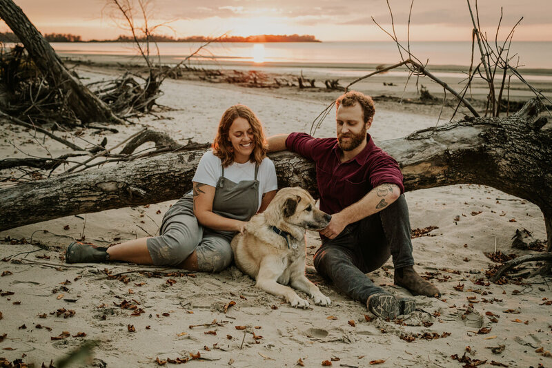 Couple sitting in the sand with their dog at Patricia Beach