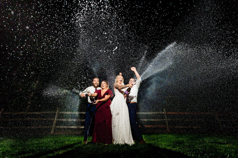 Wedding party popping bottles of champagne at night after the wedding