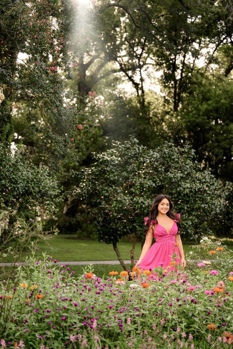 a full portrait image of a charlotte, nc senior posing amongst the flowers in charleston, sc