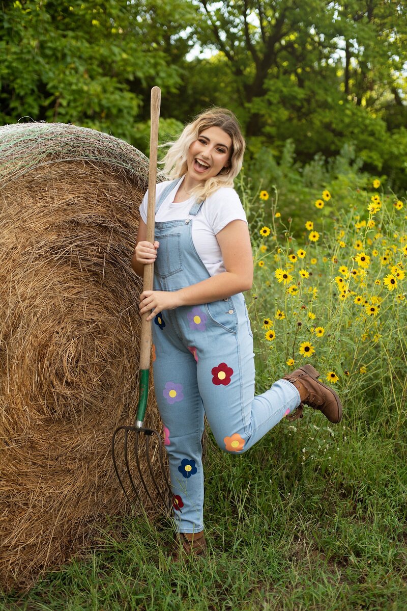 high school senior pictures farm themed shoot girls dreessed in ovralls posing with red tractor