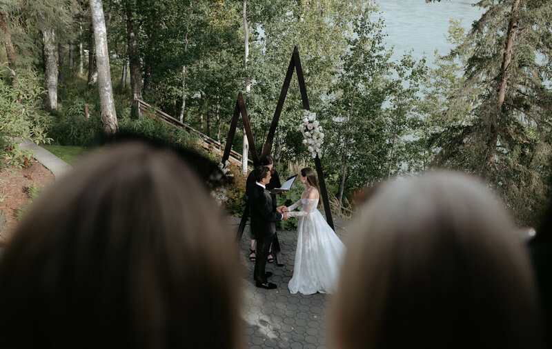 Couple holding hands in front of a triangle style arch.