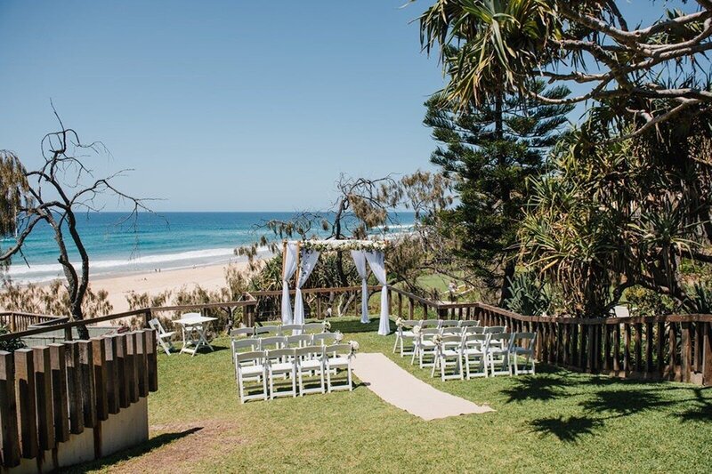 A bride and groom walking in the rain with umbrellas on the deck at Noosa Boathouse