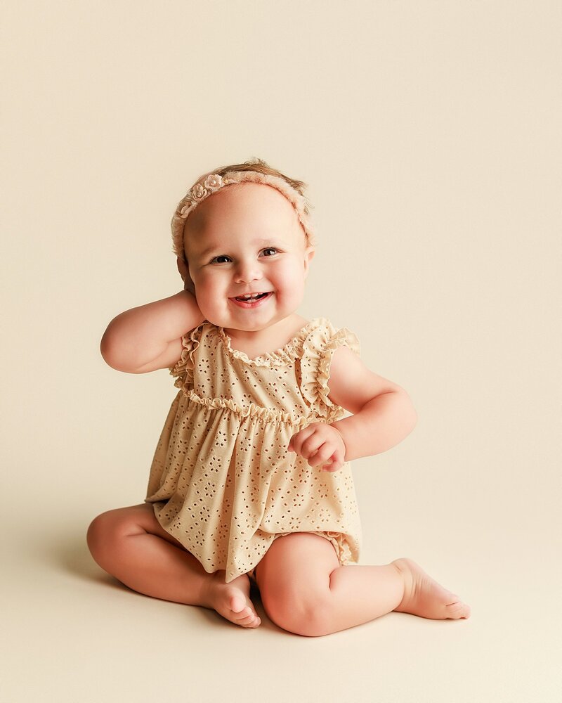 One-year-old baby in neutral romper during timeless milestone photo session