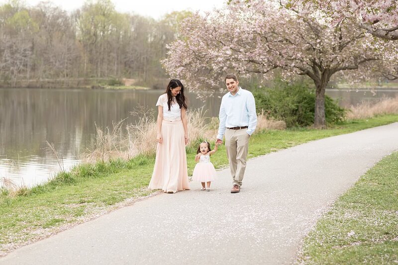 Family of 3 walking with cherry blossom tree in the background for Maryland Family Photos
