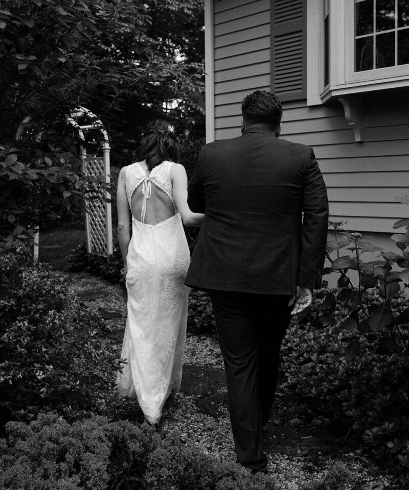 The groom and bride are walking along the path toward the house.
