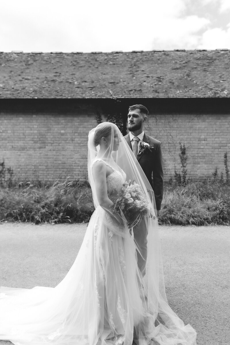 BRIDE AND GROOM KISS UNDER THE BRIDES VEIL AT THE UPTON COURT BARN AND WALLED GARDENS DURING THEIR COUPLE PORTRAITS
