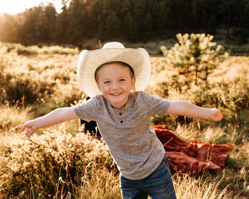 boy in a cowboy hat smiling with his arms held out wide
