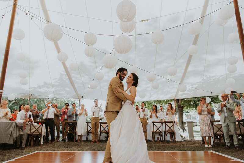 bride and groom dancing under a tent with lanterns