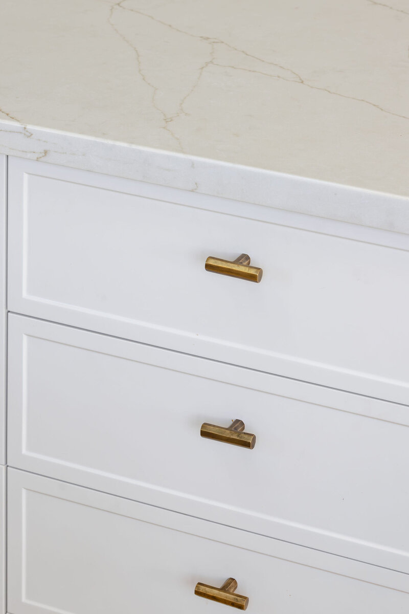 Experience bespoke interior design in Newcastle, NSW, with white kitchen drawers accented by gold handles and a sleek marble countertop.