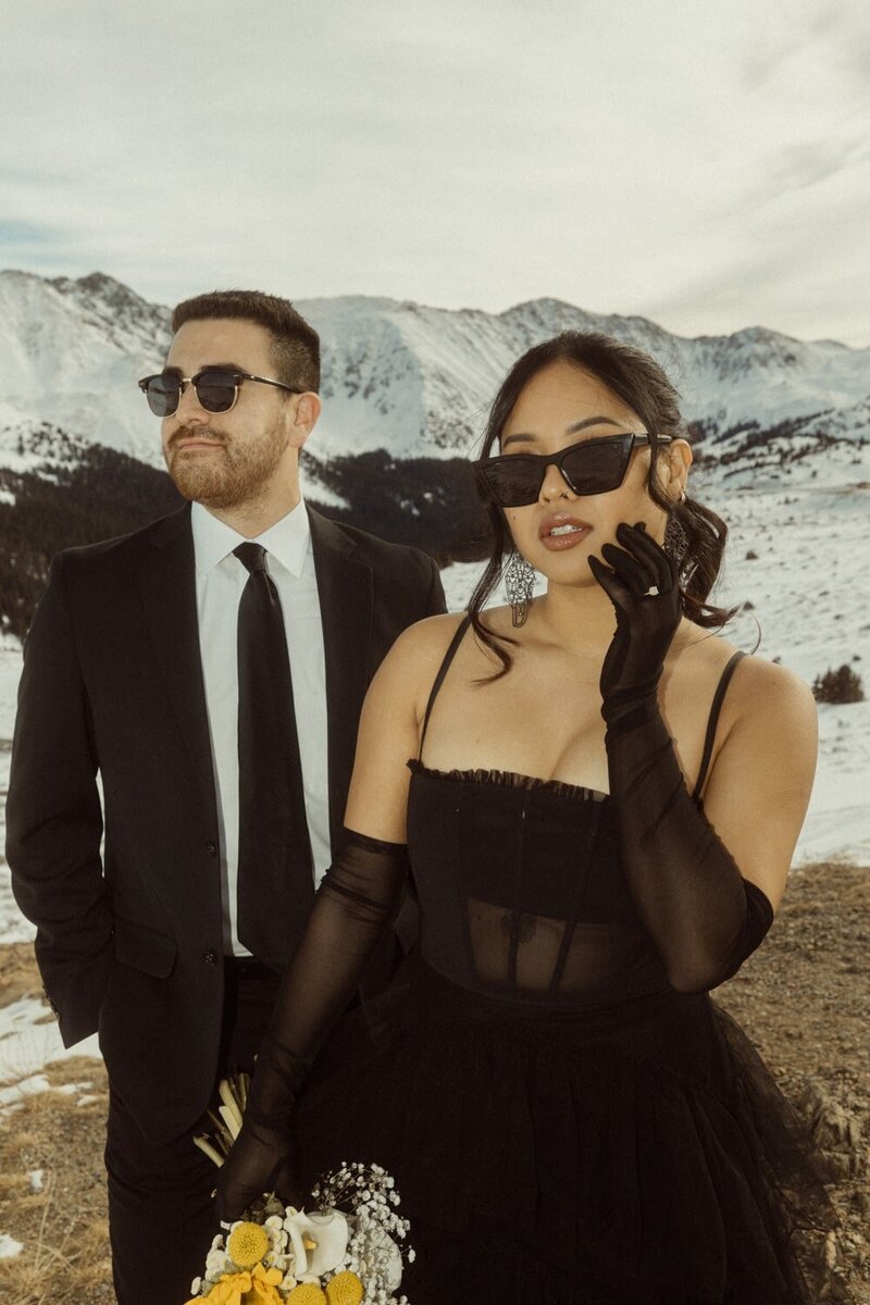 A wedding couple dressed in black on top of loveland Pass after getting married