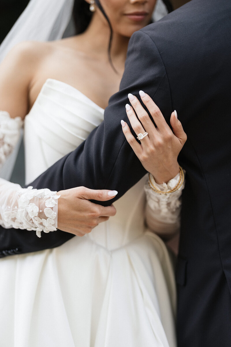 Bride and bridesmaid share a joyful moment getting ready for her wedding, hugging in soft natural light.