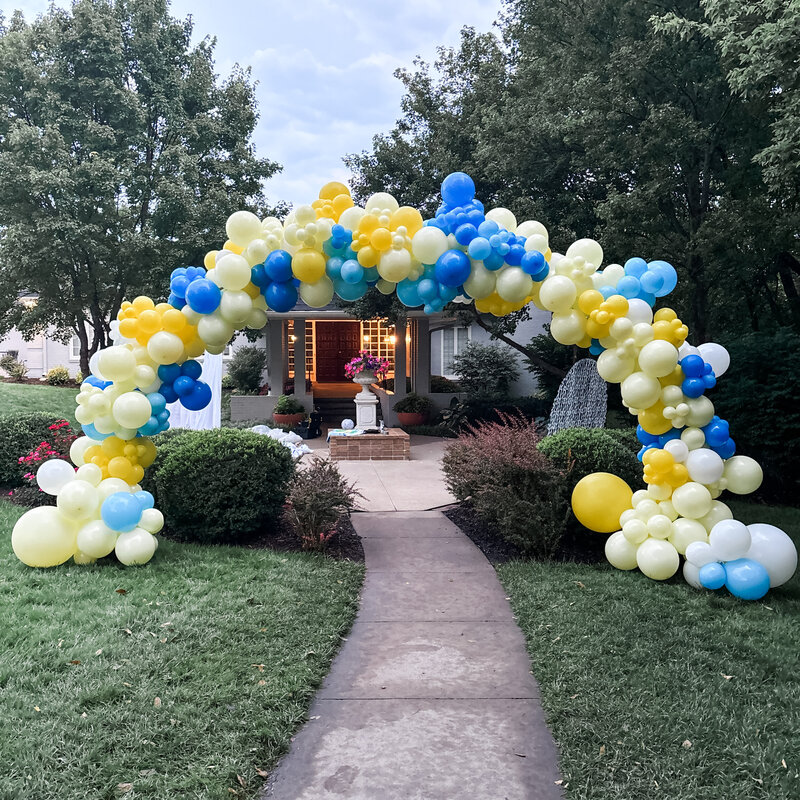 Yellow and blue balloon arch standing outside.