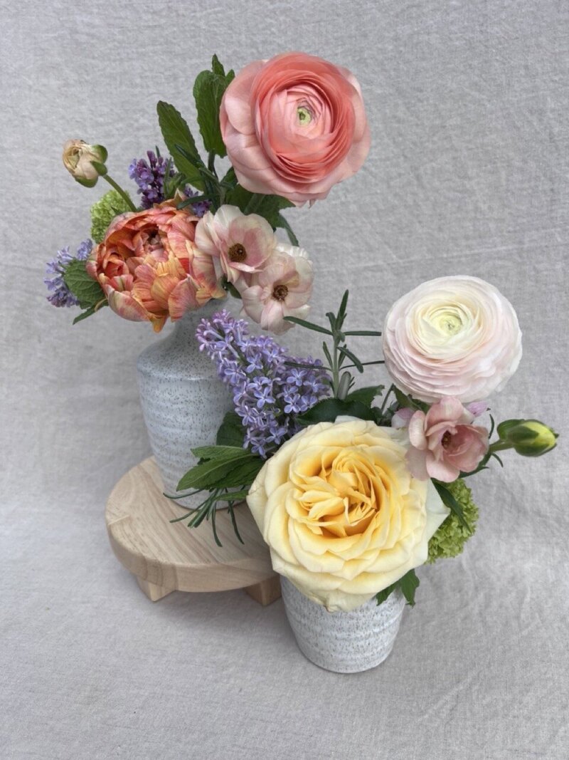 A pair of ceramic bud vases holding spring flowers, representing  Mother's Day offerings by Wild Child Flower Co. in Eugene. 