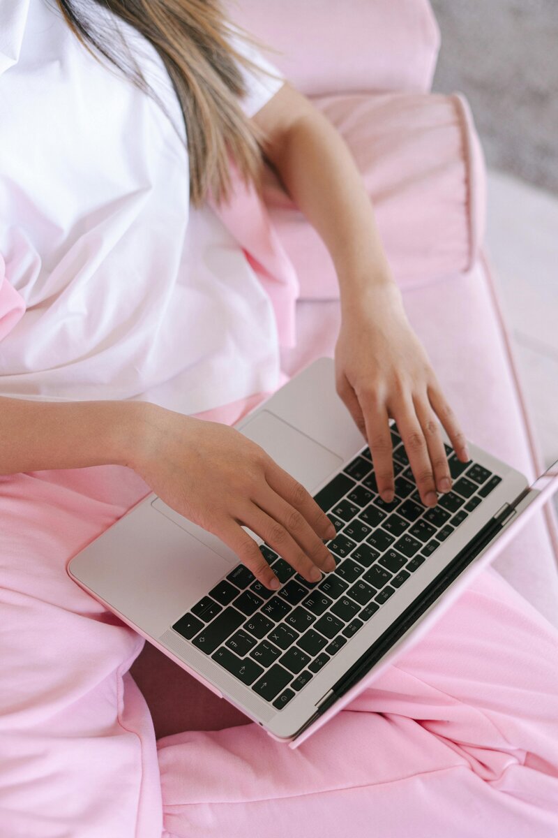 Girl in light pink on a laptop and marketing her business on pinterest