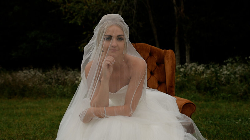 Iowa Wedding & Brand Photographer Bride sits in orange chair under veil