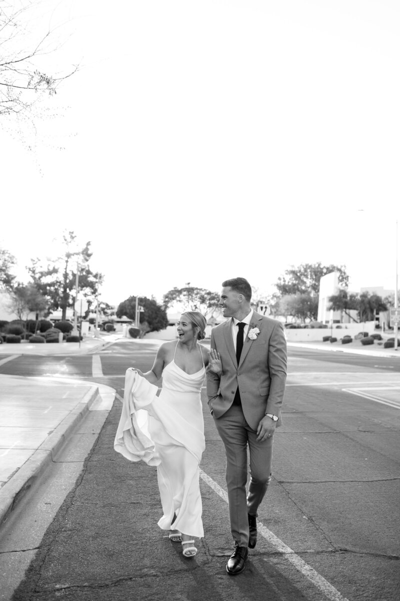 bride and groom walking at the clayton house venue in scottsdale black and white waving off camera